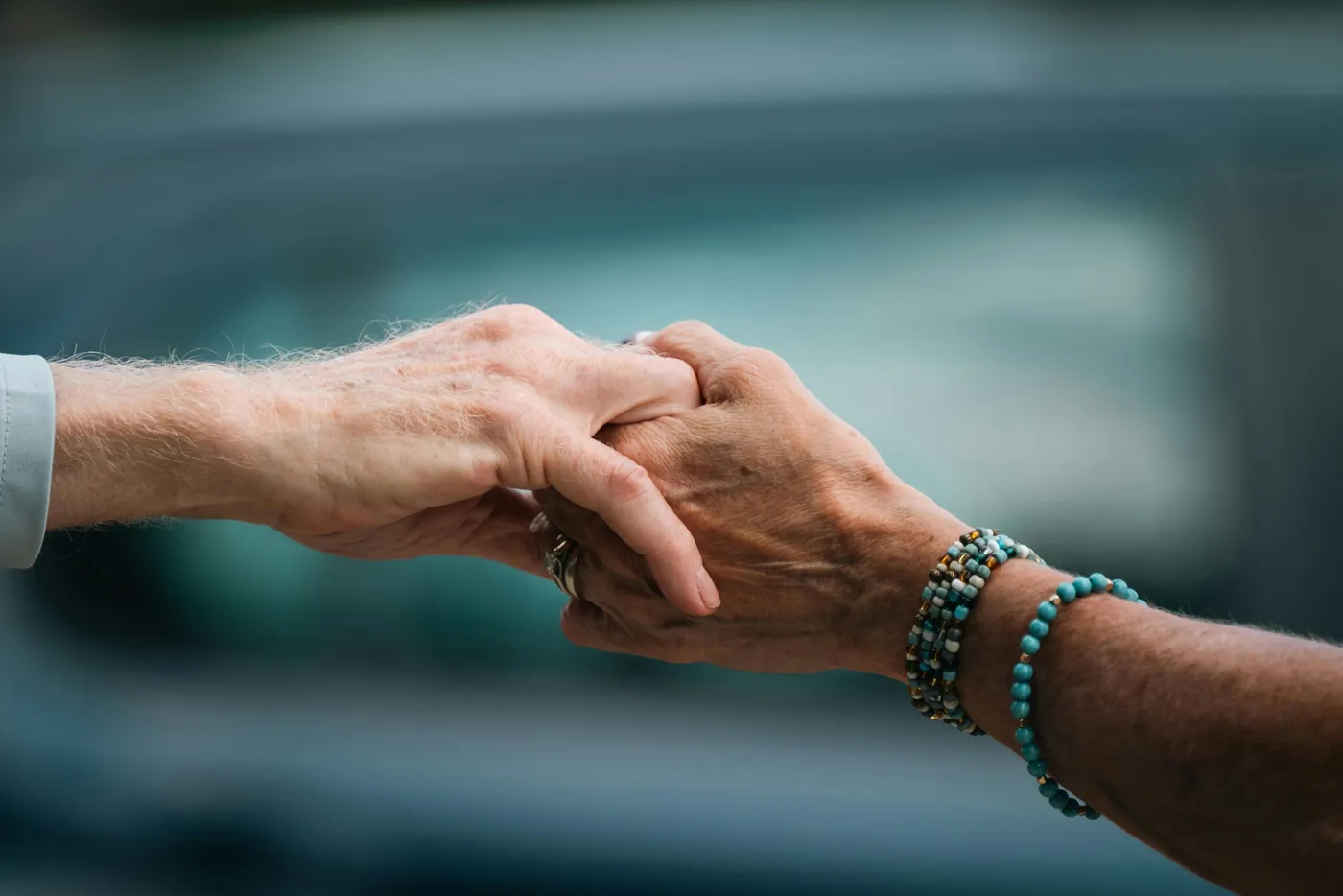 An older person's hands held gently by a carer